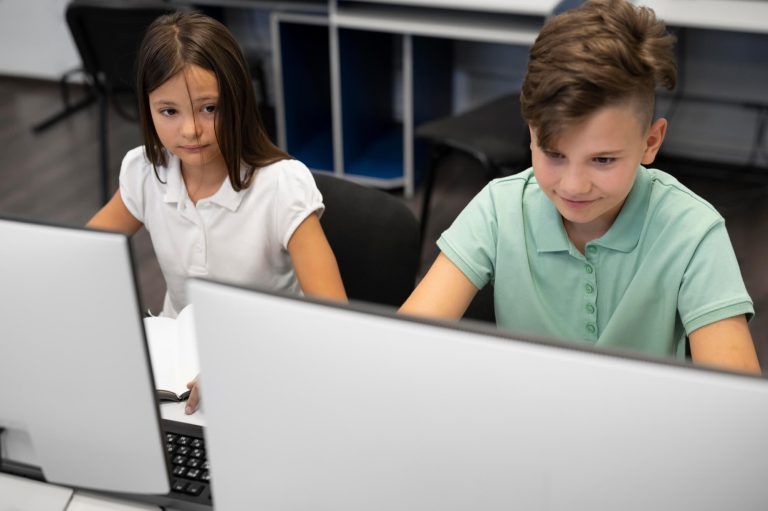 Dzieci przy komputerach w trakcie nauki tworzenia stron internetowych